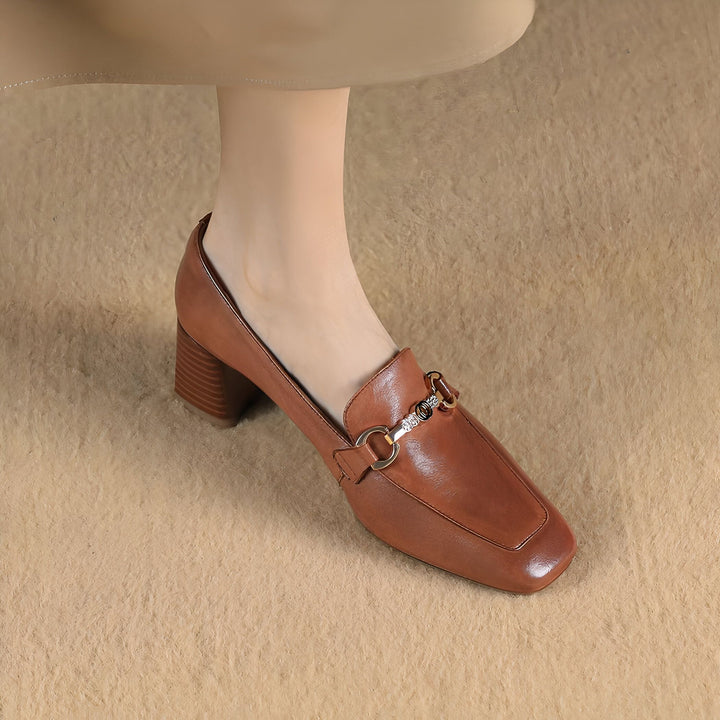 Gros plan d'un mocassin marron à talon bloc porté par une femme. La chaussure est en cuir et ornée d'une boucle dorée. Style élégant et confortable., 45287064961205,45287064993973,45287065026741,45287065059509,45287065092277,45287065125045,45287065157813,45287065190581,45287065223349,45287065256117,45287065288885,45287065321653,45287065354421,45287065387189