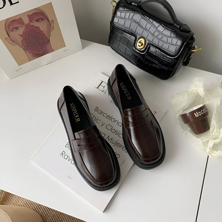 Nature morte de mode avec des mocassins en cuir marron, un sac à main noir texturé et un magazine Loewe sur une surface blanche., 45286688325813,45286688358581,45286688391349,45286688424117,45286688456885,45286688489653,45286688522421,45286688555189,45286688587957,45286688620725,45286688653493,45286688686261