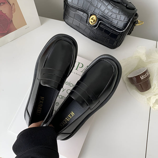 Vue rapprochée de mocassins noirs vernis pour femme, posés sur un livre avec un sac à main noir en cuir croco en arrière-plan, et une petite tasse décorative., 45286688325813,45286688358581,45286688391349,45286688424117,45286688456885,45286688489653,45286688522421,45286688555189,45286688587957,45286688620725,45286688653493,45286688686261