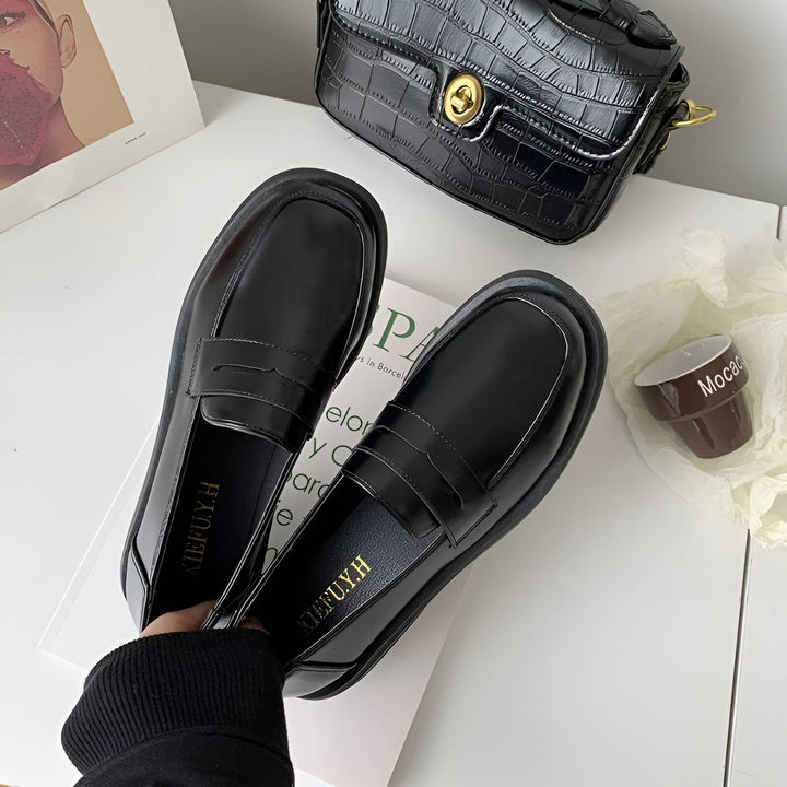 Vue rapprochée de mocassins noirs vernis pour femme, posés sur un livre avec un sac à main noir en cuir croco en arrière-plan, et une petite tasse décorative., 45286688325813,45286688358581,45286688391349,45286688424117,45286688456885,45286688489653,45286688522421,45286688555189,45286688587957,45286688620725,45286688653493,45286688686261