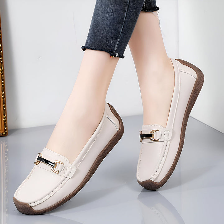 Gros plan sur une personne portant des mocassins en cuir blanc cassé avec une boucle décorative dorée, associés à un jean noir décontracté. Chaussures confortables et élégantes, idéales pour un look quotidien., 45286854164661,45286854197429,45286854230197,45286854262965,45286854295733,45286854328501,45286854361269,45286854394037,45286854426805,45286854459573,45286854492341,45286854525109,45286854557877,45286854590645,45286854623413,45286854656181,45286854688949,45286854721717,45286854754485,4528