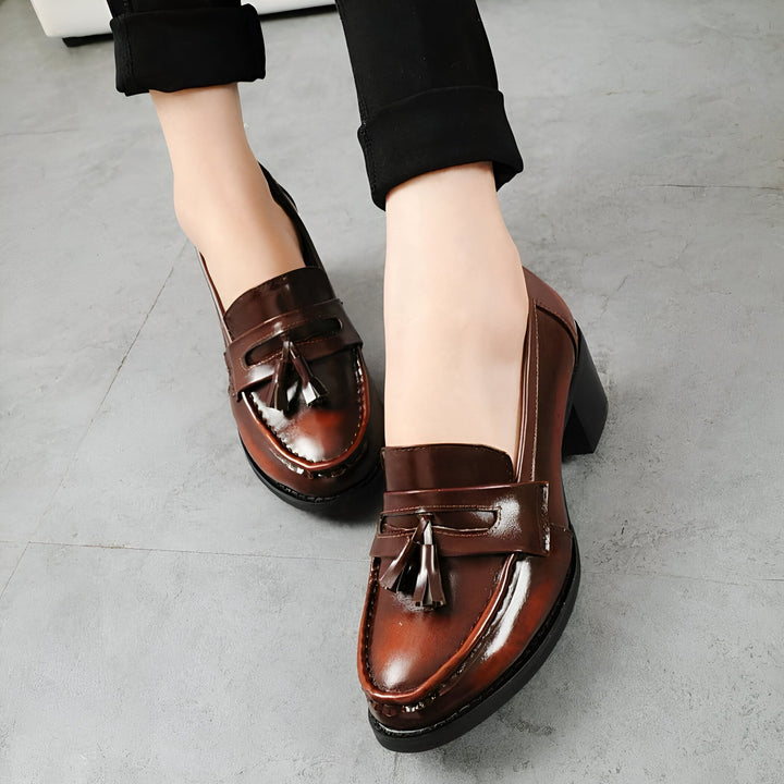 Gros plan sur des chaussures à talons marron vernies de style mocassins à glands, portées avec un pantalon noir. Élégance et confort pour une tenue féminine., 45287057490101,45287057522869,45287057555637,45287057588405,45287057621173,45287057653941,45287057686709,45287057719477,45287057752245,45287057785013,45287057817781,45287057850549,45287057883317,45287057916085,45287057948853,45287057981621,45287058014389,45287058047157,45287058079925,45287058112693,45287058145461,45287058178229,45287058210997,