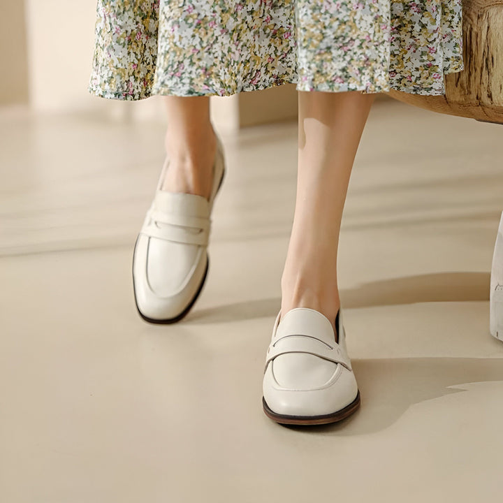 Gros plan des pieds d'une femme portant des mocassins en cuir blanc cassé et une robe à fleurs. Chaussures élégantes, tenue décontractée., 45286733414581,45286733447349,45286733480117,45286733512885,45286733545653,45286733578421,45286733611189