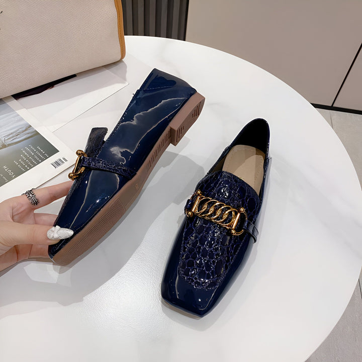 Mocassins vernis bleu marine pour femme sur table. Détail d'une chaîne dorée et d'un motif crocodile. Mode élégante et tendance. Chaussures de ville confortables., 45286865436853,45286865469621,45286865502389,45286865535157,45286865567925,45286865600693,45286865633461,45286865666229,45286865698997,45286865731765,45286865764533,45286865797301,45286865830069,45286865862837