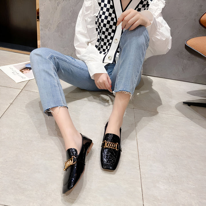 Femme assise sur le sol, portant un cardigan à carreaux noir et blanc, un jean bleu clair et des mocassins noirs vernis avec une chaîne dorée. Mode féminine, chaussures élégantes, style décontracté., 45286865436853,45286865469621,45286865502389,45286865535157,45286865567925,45286865600693,45286865633461,45286865666229,45286865698997,45286865731765,45286865764533,45286865797301,45286865830069,45286865862837