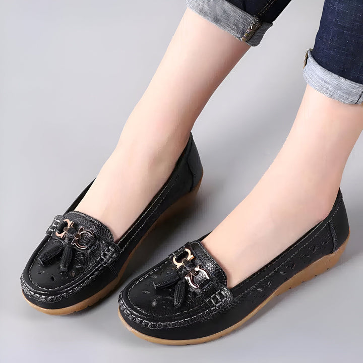 Chaussures mocassins noires portées par une femme avec un jean. Mocassins en cuir avec un ornement doré. Chaussures décontractées et confortables., 45287003357365,45287003390133,45287003422901,45287003455669,45287003488437,45287003521205,45287003553973,45287003586741,45287003619509,45287003652277,45287003685045,45287003717813,45287003750581,45287003783349,45287003816117,45287003848885,45287003881653,45287003914421,45287003947189,45287003979957,45287004012725,45287004045493,45287004078261,4528700411102