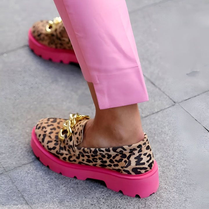 Détail de chaussures léopard à semelles roses vives portées avec un pantalon rose. Chaussures mocassins avec détail de chaîne dorée. Mode audacieuse., 45286832406709,45286832439477,45286832472245,45286832505013,45286832537781,45286832570549,45286832603317,45286832636085