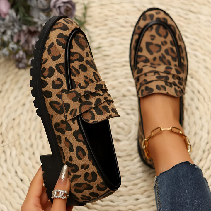 Mocassins femme à motif léopard, avec semelles épaisses, présentés de près sur un fond neutre. Une main tient une chaussure, l'autre pied est visible avec une chaîne de cheville dorée et un jean bleu., 45286625870005,45286625902773,45286625935541,45286625968309,45286626001077,45286626033845,45286626066613,45286626099381