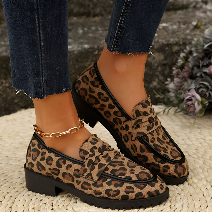 Chaussures mocassins pour femmes avec imprimé léopard, associées à un jean bleu et une chaîne de cheville dorée, reposant sur un tapis tressé. Mode et élégance., 45286625870005,45286625902773,45286625935541,45286625968309,45286626001077,45286626033845,45286626066613,45286626099381