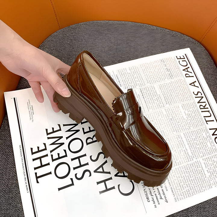 Mocassin marron à plateforme vernis sur un journal "The Loewe Show Has Re". Une main tient la chaussure. Accessoire de mode élégant et tendance. Style moderne et original. Idée cadeau femme. Automne-hiver 2021., 45286908330165,45286908362933,45286908395701,45286908428469,45286908461237,45286908494005,45286908526773,45286908559541,45286908592309,45286908625077,45286908657845,45286908690613