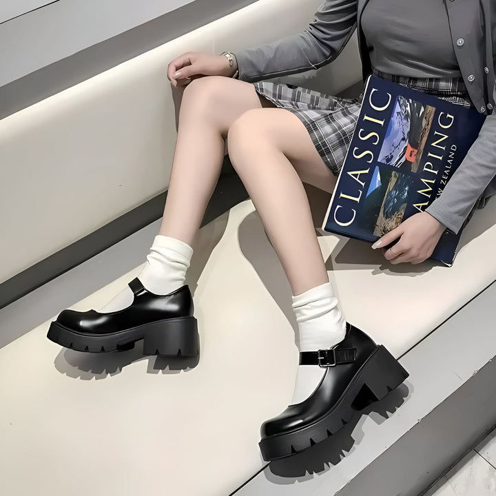 Une femme assise, portant des chaussures Mary Jane à plateforme noires avec des chaussettes blanches, tenant un livre intitulé "Classic Camping New Zealand". Vêtements gris et jupe à carreaux., 45286685573301,45286685606069,45286685638837,45286685671605,45286685704373,45286685737141,45286685769909,45286685802677,45286685835445,45286685868213,45286685900981,45286685966517