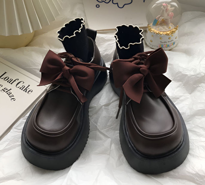 Paire de chaussures marron à plateforme avec lacets ornés de noeuds en satin marron. On aperçoit des chaussettes noires à bordure blanche., 45286886375605,45286886408373,45286886441141,45286886473909,45286886506677,45286886539445,45286886572213,45286886604981,45286886637749,45286886670517,45286886703285,45286886736053