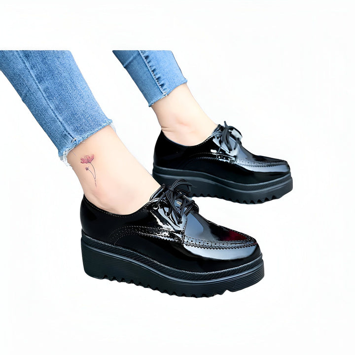 Chaussures Oxford noires vernies à semelles compensées, portées avec un jean bleu. On aperçoit un tatouage de fleur sur la cheville. Style moderne et élégant., 45286905774261,45286905807029,45286905839797,45286905872565,45286905905333