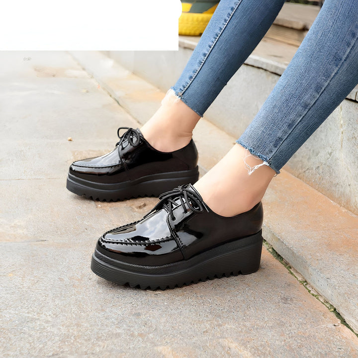 Gros plan de chaussures derby noires vernies à plateforme, portées avec un jean bleu délavé. Mode chaussures femme, style tendance et confort., 45286905774261,45286905807029,45286905839797,45286905872565,45286905905333