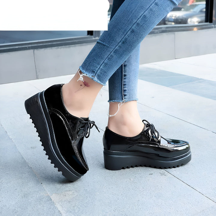 Gros plan sur des chaussures Oxford noires vernies portées avec un jean découpé. Chaussures de ville à plateforme, lacets noirs fins. Mode féminine, chaussures élégantes., 45286905774261,45286905807029,45286905839797,45286905872565,45286905905333