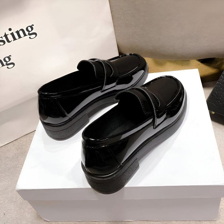 Deux mocassins vernis noirs brillants, posés sur une boîte blanche. Chaussures élégantes pour femmes, style classique., 45286950895797,45286950928565,45286950961333,45286950994101,45286951026869,45286951059637
