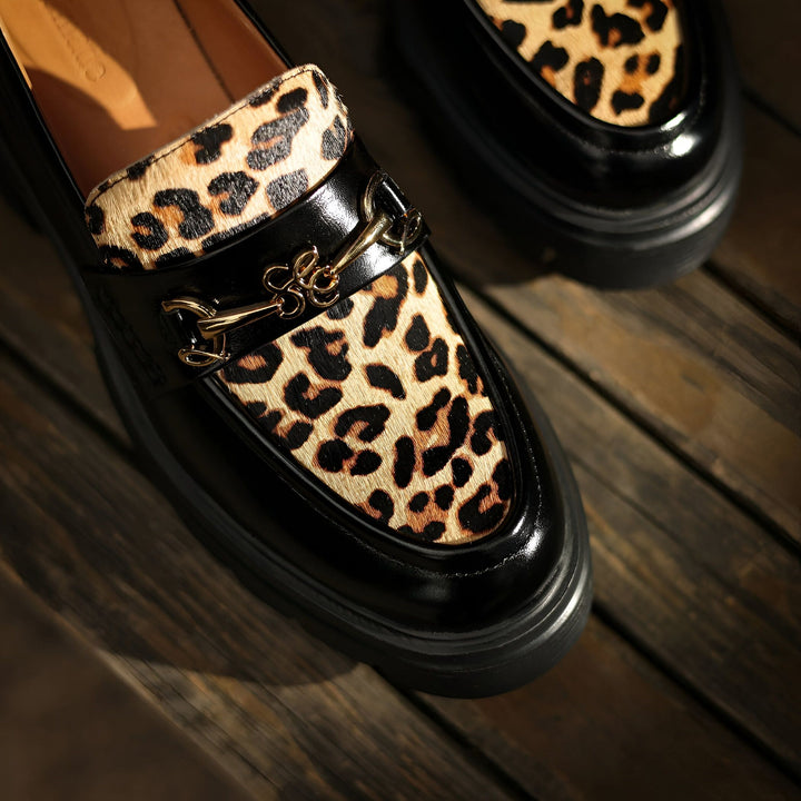 Mocassins en cuir noir avec imprimé léopard et détails dorés, sur fond de bois. Chaussures élégantes pour femmes, style tendance., 45286649594037,45286649626805,45286649659573,45286649692341,45286649725109