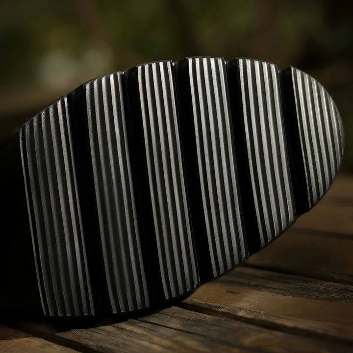 Gros plan d'une semelle de chaussure noire avec des rainures profondes, offrant une bonne adhérence. Texture robuste pour une marche stable., 45286649594037,45286649626805,45286649659573,45286649692341,45286649725109