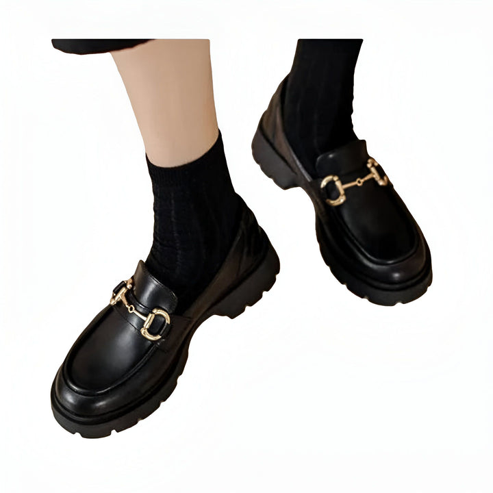 Gros plan de mocassins noirs à semelle épaisse avec boucles dorées portés avec des chaussettes noires. Mode automne-hiver, chaussures élégantes., 45286717653173,45286717685941,45286717718709,45286717751477,45286717784245,45286717817013,45286717849781