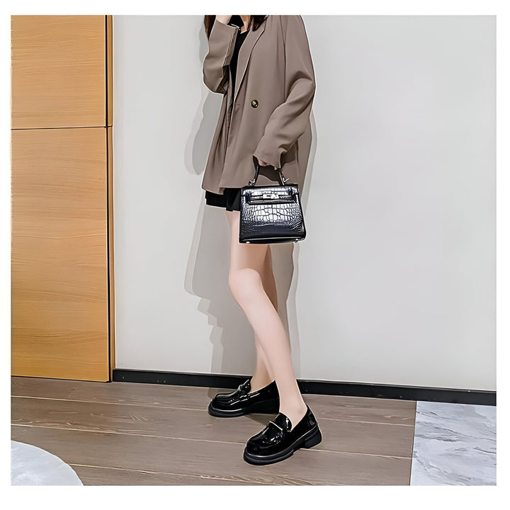 Femme élégante en blazer marron, jupe noire et mocassins noirs vernis, tenant un sac à main noir texturé. Mode automne-hiver, style classique., 45286714671285,45286714704053,45286714736821,45286714769589,45286714802357,45286714835125,45286714867893,45286714900661,45286714933429