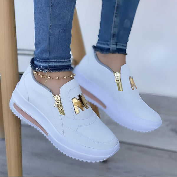 Gros plan de baskets blanches à plateforme pour femme avec fermeture éclair dorée et logo "M". Portées avec un jean bleu et une chaîne de cheville dorée. Mode, chaussures de sport, style décontracté., 45286880313525,45286880346293,45286880379061,45286880411829,45286880444597,45286880477365,45286880510133,45286880542901,45286880575669,45286880608437,45286880641205,45286880673973,45286880706741,45286880739509,45286880772277,45286880805045,45286880837813,45286880870581,45286880903349,45286880936117,4