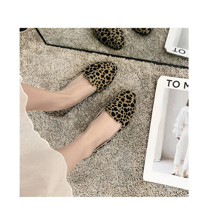 Gros plan sur des chaussures plates à motif léopard portées par une personne sur un tapis texturé. On aperçoit également un miroir et une revue de mode., 45287150485685,45287150518453,45287150551221,45287150583989,45287150616757,45287150649525,45287150682293,45287150715061,45287150747829