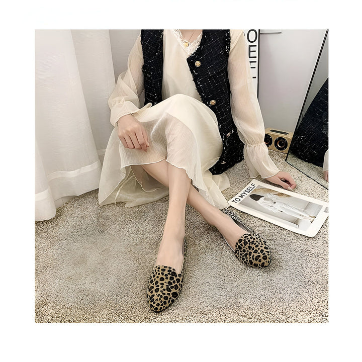 Femme assise sur un tapis, robe blanche fluide, gilet noir texturé. Chaussures plates à motifs léopard. Magazine de mode ouvert à ses côtés. Décor intérieur moderne et épuré., 45287150485685,45287150518453,45287150551221,45287150583989,45287150616757,45287150649525,45287150682293,45287150715061,45287150747829