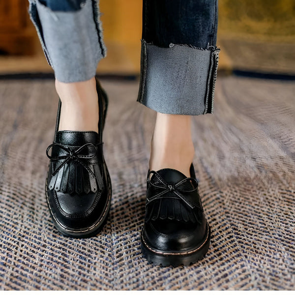 Gros plan de mocassins noirs à glands et noeud décoratif, portés avec un jean à revers. Style élégant et décontracté. Chaussures en cuir verni., 45286718308533,45286718341301,45286718374069,45286718406837,45286718439605,45286718472373,45286718505141,45286718537909,45286718570677,45286718603445,45286718636213,45286718668981,45286718701749,45286718734517