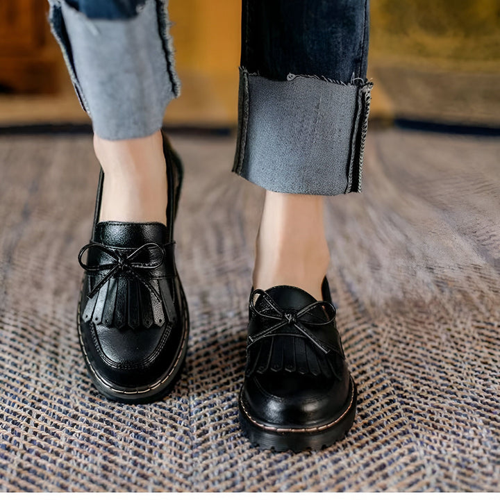 Gros plan de mocassins noirs à glands et noeud décoratif, portés avec un jean à revers. Style élégant et décontracté. Chaussures en cuir verni., 45286718308533,45286718341301,45286718374069,45286718406837,45286718439605,45286718472373,45286718505141,45286718537909,45286718570677,45286718603445,45286718636213,45286718668981,45286718701749,45286718734517