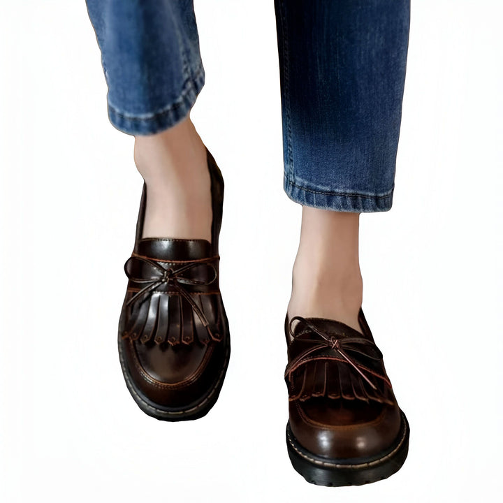 Gros plan de mocassins à franges en cuir marron portés avec un jean bleu, mettant en valeur le style décontracté et élégant des chaussures pour femmes. Chaussures tendance avec détails de nœud., 45286718308533,45286718341301,45286718374069,45286718406837,45286718439605,45286718472373,45286718505141,45286718537909,45286718570677,45286718603445,45286718636213,45286718668981,45286718701749,45286718734517