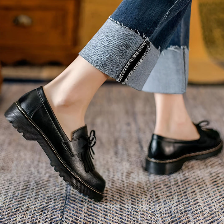 Gros plan sur des mocassins noirs en cuir portés avec un jean retroussé. Chaussures élégantes avec détails de glands et semelles épaisses. Mode décontractée et confortable., 45286718308533,45286718341301,45286718374069,45286718406837,45286718439605,45286718472373,45286718505141,45286718537909,45286718570677,45286718603445,45286718636213,45286718668981,45286718701749,45286718734517