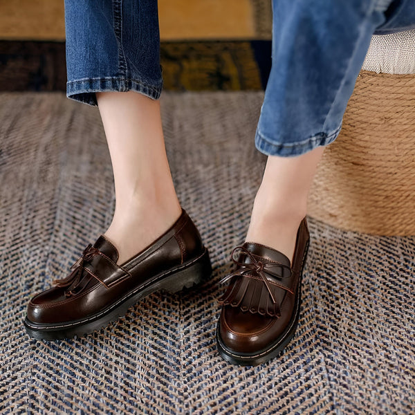 Gros plan de pieds portant des mocassins à glands en cuir marron avec un jean bleu, sur un tapis texturé. Chaussures élégantes et confortables pour un look décontracté et chic., 45286718308533,45286718341301,45286718374069,45286718406837,45286718439605,45286718472373,45286718505141,45286718537909,45286718570677,45286718603445,45286718636213,45286718668981,45286718701749,45286718734517