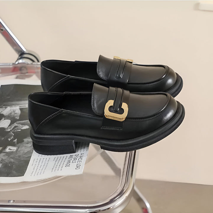 Deux mocassins noirs vernis avec boucle dorée reposent sur un journal et une chaise transparente. Chaussures élégantes pour femmes, tendance automne-hiver., 45286718767285,45286718800053,45286718832821,45286718865589,45286718898357,45286718931125,45286718963893,45286718996661,45286719029429,45286719062197,45286719094965,45286719127733,45286719160501,45286719193269,45286719226037,45286719258805,45286719291573,45286719324341,45286719357109,45286719389877