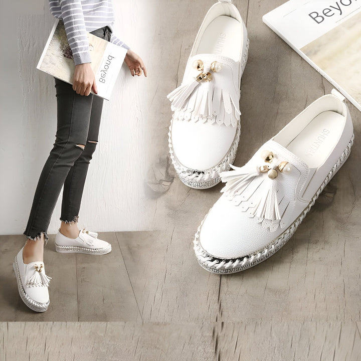 Chaussures blanches à glands portées par une femme, avec une autre paire de chaussures blanches à glands posée à côté d'un livre sur un sol en bois., 45286766313653,45286766346421,45286766379189,45286766411957,45286766444725,45286766477493,45286766510261,45286766543029,45286766575797,45286766608565,45286766641333,45286766674101