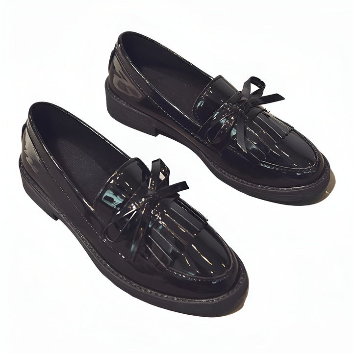 Une paire de mocassins noirs vernis avec des franges et un nœud décoratif. Chaussures élégantes et brillantes pour femme. Mode et style., 45287001292981,45287001325749,45287001358517,45287001391285,45287001424053,45287001456821,45287001489589,45287001522357,45287001555125,45287001587893