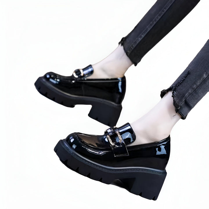 Gros plan sur des mocassins noirs vernis à semelle épaisse, portés avec un jean noir. Chaussures mode pour femme avec détails métalliques brillants. Style audacieux et tendance., 45286884704437,45286884737205,45286884769973,45286884802741,45286884835509,45286884868277,45286884901045,45286884933813,45286884966581,45286884999349,45286885032117,45286885064885