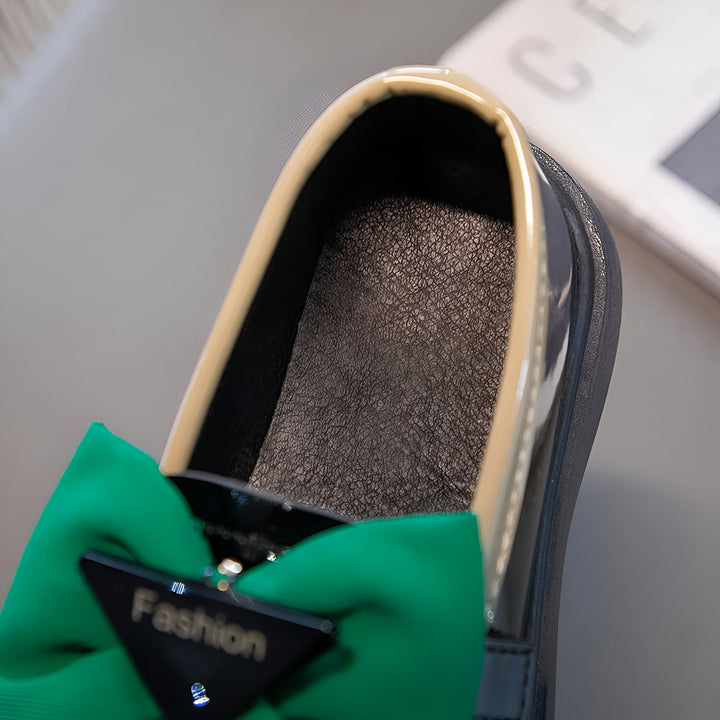 Vue rapprochée d'une chaussure plate noire vernie pour enfant, avec un nœud vert vif et un détail triangulaire "Fashion". Intérieur texturé et bordure beige. Mode enfantine et élégance., 45287024033973,45287024066741,45287024099509,45287024132277,45287024165045,45287024197813,45287024230581,45287024263349,45287024296117,45287024328885,45287024361653,45287024394421,45287024427189,45287024459957,45287024492725,45287024525493,45287024558261,45287024591029,45287024623797,45287024656565,45287024689333,4