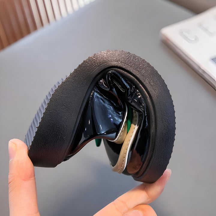 Gros plan d'une chaussure vernie noire pour enfant pliée à la main, montrant la semelle texturée et le design flexible. Détails des matériaux et de la fabrication., 45287024033973,45287024066741,45287024099509,45287024132277,45287024165045,45287024197813,45287024230581,45287024263349,45287024296117,45287024328885,45287024361653,45287024394421,45287024427189,45287024459957,45287024492725,45287024525493,45287024558261,45287024591029,45287024623797,45287024656565,45287024689333,45287024722101,4528702475