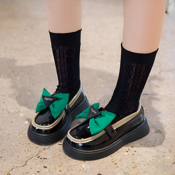 Chaussures vernies noires avec des nœuds verts portant la mention "Fashion", portées avec des chaussettes noires ajourées., 45287024033973,45287024066741,45287024099509,45287024132277,45287024165045,45287024197813,45287024230581,45287024263349,45287024296117,45287024328885,45287024361653,45287024394421,45287024427189,45287024459957,45287024492725,45287024525493,45287024558261,45287024591029,45287024623797,45287024656565,45287024689333,45287024722101,45287024754869,45287024787637,45287024820405,45287024