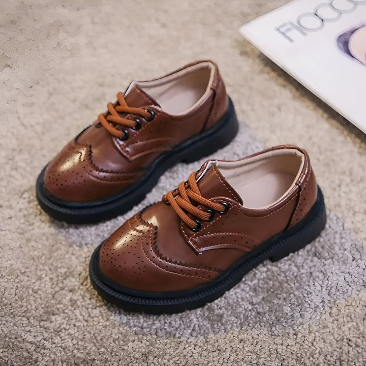 Deux chaussures richelieu marron pour enfants avec lacets orange sur un tapis texturé. Chaussures habillées en cuir pour garçon., 45286680232117,45286680264885,45286680297653,45286680330421,45286680363189,45286680395957,45286680428725,45286680461493,45286680494261,45286680527029,45286680559797,45286680592565,45286680625333,45286680658101,45286680690869,45286680723637,45286680756405,45286680789173,45286680821941,45286680854709,45286680887477,45286680920245