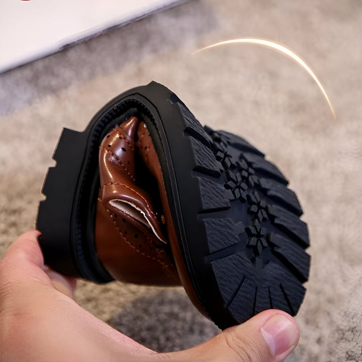 Gros plan sur une chaussure pour enfant en cuir marron, pliée pour montrer sa flexibilité. La semelle noire est visible, offrant une bonne adhérence. Idéale pour un look élégant et confortable., 45286680232117,45286680264885,45286680297653,45286680330421,45286680363189,45286680395957,45286680428725,45286680461493,45286680494261,45286680527029,45286680559797,45286680592565,45286680625333,45286680658101,45286680690869,45286680723637,45286680756405,45286680789173,45286680821941,45286680854709,452866808