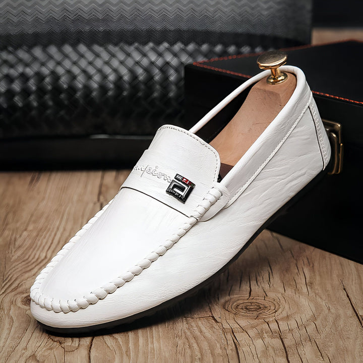 Mocassin blanc pour homme, détail couture visible, orné d'une boucle avec logo, sur fond de boîte noire et parquet. Élégance et style pour toutes occasions., 45286788006069,45286788038837,45286788071605,45286788104373,45286788137141,45286788169909