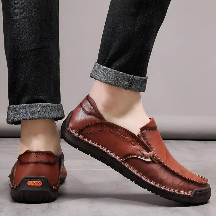 Un homme portant des mocassins en cuir marron avec un jean noir retroussé. Chaussures décontractées pour homme, style loafer en cuir., 45286710182069,45286710214837,45286710247605,45286710280373,45286710313141,45286710345909,45286710378677,45286710411445,45286710444213,45286710476981,45286710509749,45286710542517,45286710575285,45286710608053,45286710640821,45286710673589,45286710706357,45286710739125,45286710771893,45286710837429,45286710870197,45286710902965,45286710935733,45286710968501,452867110012