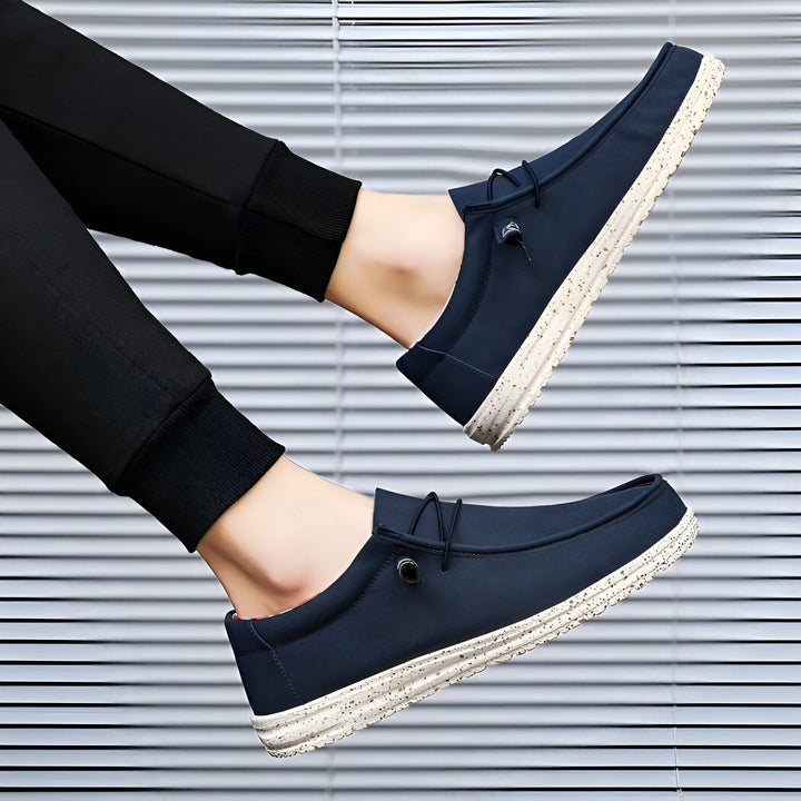 Vue rapprochée de chaussures décontractées bleu marine pour hommes, avec semelle mouchetée blanche, portées avec un pantalon de survêtement noir., 45286677643445,45286677676213,45286677708981,45286677741749,45286677774517,45286677807285,45286677840053,45286677872821,45286677905589,45286677938357,45286677971125,45286678003893,45286678036661,45286678069429,45286678102197,45286678134965,45286678167733,45286678200501