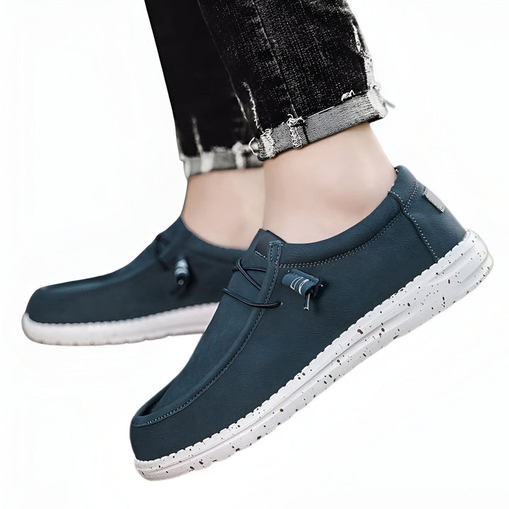 Gros plan d'une paire de chaussures décontractées bleu pétrole avec des lacets élastiques et une semelle blanche mouchetée, portées avec un jean noir retroussé., 45286686621877,45286686654645,45286686687413,45286686720181,45286686752949,45286686785717,45286686818485,45286686851253,45286686884021,45286686916789,45286686949557,45286686982325,45286687015093,45286687047861,45286687080629,45286687113397,45286687146165,45286687178933,45286687211701,45286687244469,45286687277237