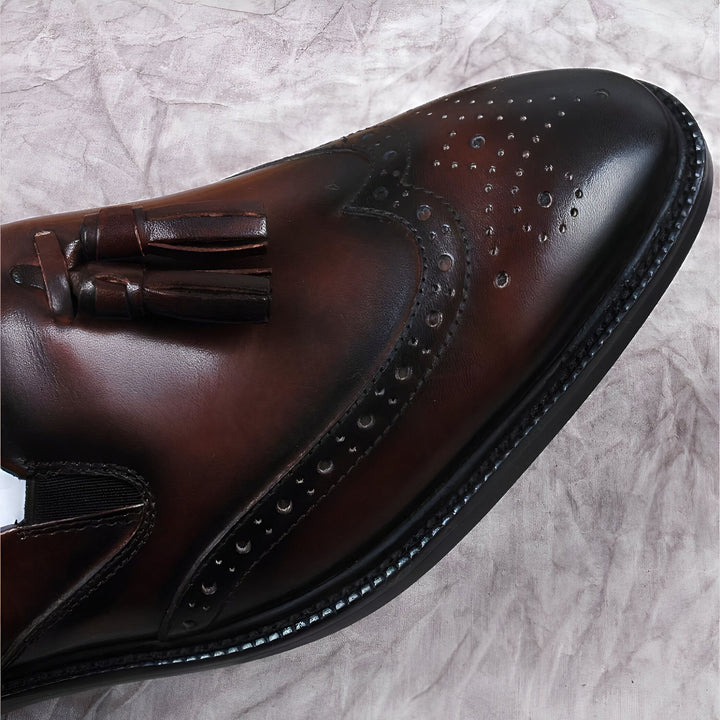 Gros plan sur une élégante chaussure marron en cuir avec des perforations décoratives et un pompon. Détails raffinés et artisanat de qualité., 45286843941045,45286843973813,45286844006581,45286844039349,45286844072117,45286844104885,45286844137653