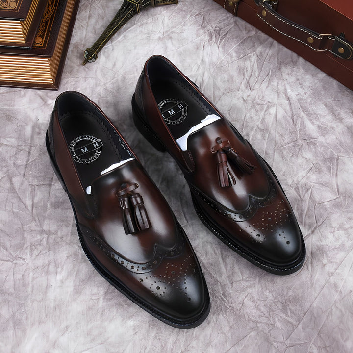 Gros plan sur une paire de mocassins à glands en cuir marron pour homme, avec des détails perforés. Style élégant et classique pour une occasion spéciale. Valise et Tour Eiffel miniatures en arrière-plan., 45286843941045,45286843973813,45286844006581,45286844039349,45286844072117,45286844104885,45286844137653