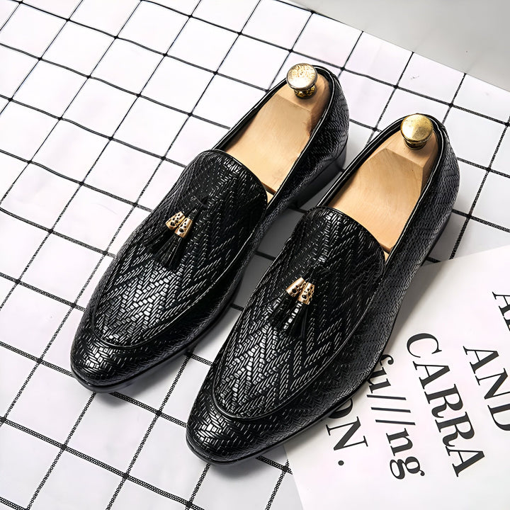 Image de deux mocassins noirs texturés avec des glands dorés, placés sur un fond à carreaux et un document partiellement visible. Ces chaussures élégantes présentent des embauchoirs en bois., 45286928122037,45286928154805,45286928187573,45286928220341,45286928253109,45286928285877,45286928318645,45286928351413,45286928384181,45286928416949,45286928449717,45286928482485,45286928515253,45286928548021