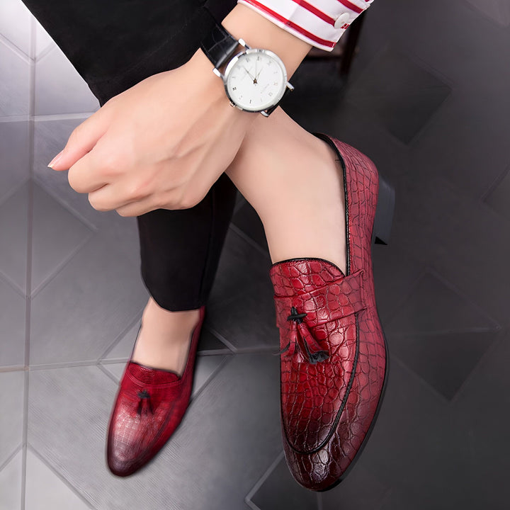 Gros plan sur des mocassins rouges à glands, motif peau de crocodile, portés avec un pantalon noir et une chemise rayée. On aperçoit une montre au poignet. Chaussures élégantes pour homme., 45287059423413,45287059456181,45287059488949,45287059521717,45287059554485,45287059587253,45287059620021,45287059652789,45287059685557,45287059718325,45287059751093,45287059783861,45287059816629,45287059849397,45287059882165,45287059914933,45287059947701,45287059980469,45287060013237,45287060046005,45287060078773