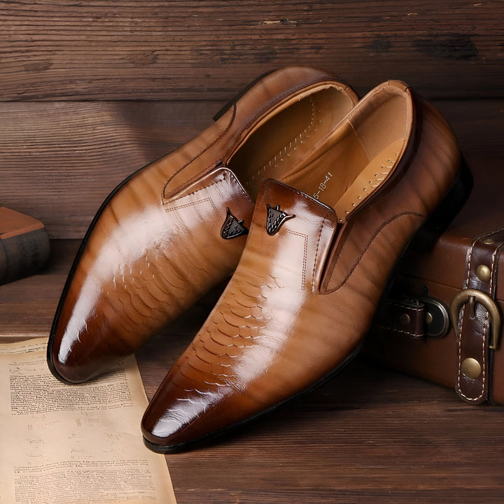 Chaussures élégantes en cuir marron pour hommes, style mocassins avec motif peau de serpent et détail métallique sur le dessus. Contexte en bois avec une valise vintage et un livre., 45287064010933,45287064043701,45287064076469,45287064109237,45287064142005,45287064174773,45287064207541,45287064240309,45287064273077,45287064305845,45287064338613,45287064371381,45287064404149,45287064436917,45287064469685,45287064502453,45287064535221,45287064567989,45287064600757,45287064633525,45287064666293,45287064
